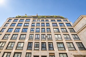 Ein mehrgeschossiges Gebäude mit einheitlicher Fassade, zahlreichen Fenstern und einem begrünten Flachdach.