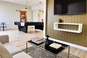 A modern living room with a pool table, a sofa, a coffee table, and a mounted TV. - Loft con vista al mar y piscina Barranco (Barranco)