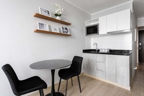 A modern kitchen with a microwave, sink, and cabinets. There is a dining table with two chairs. - Loft con vista al mar y piscina Barranco (Barranco)