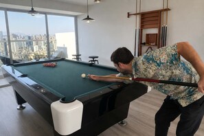 A pool table in a room with a city view, a pool cue, and a billiard rack. - Loft con vista al mar y piscina Barranco (Barranco)