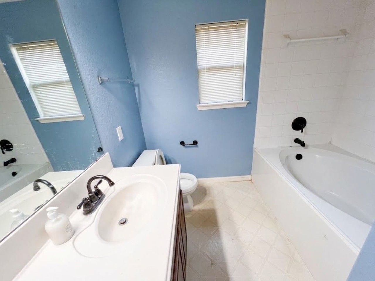 A bathroom with a white bathtub, a double sink, and a toilet.