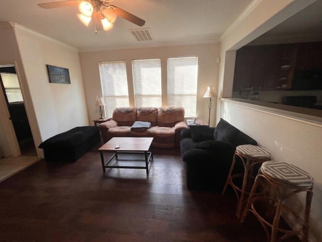 A living room with a sofa, two armchairs, a coffee table, and a TV.