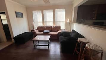 A living room with a sofa, two armchairs, a coffee table, and a TV.