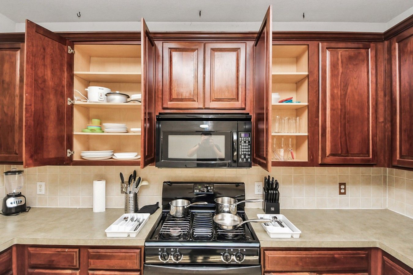 A kitchen with wooden cabinets, a stove, a microwave, and a blender.
