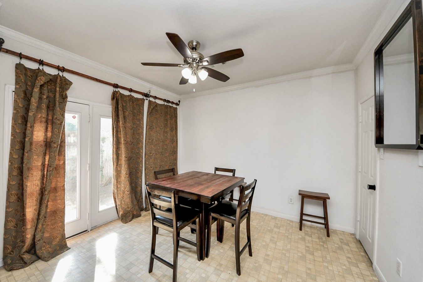 A dining room with a wooden table and chairs, a ceiling fan, and a small side table.