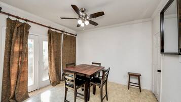 A dining room with a wooden table and chairs, a ceiling fan, and a small side table.