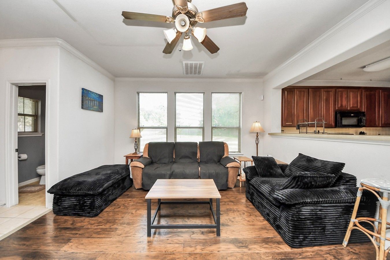 A living room with a sofa set, a coffee table, and a ceiling fan.