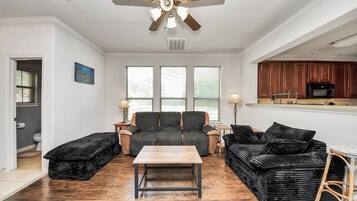 A living room with a sofa set, a coffee table, and a ceiling fan.