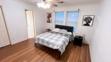 A bedroom with a bed, a ceiling fan, a window, and a door.