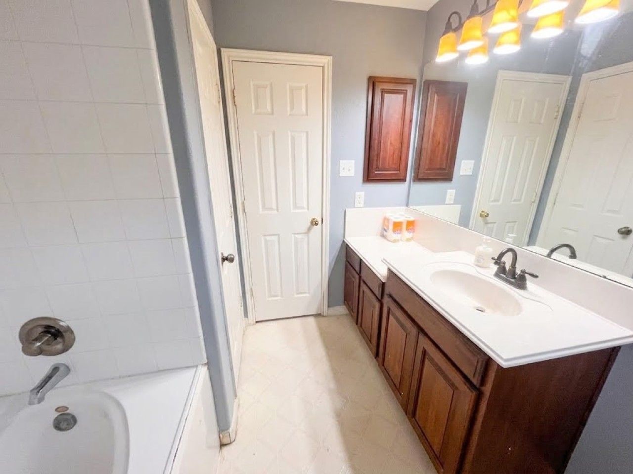 Une salle de bain avec une baignoire blanche, un lavabo avec un miroir au-dessus, et des meubles en bois.