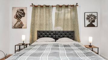 A bedroom with a bed, two bedside tables, a headboard, and two wall-mounted lamps.