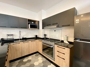 A modern kitchen with grey cabinets, a stainless steel stove, and a built-in microwave. - 2BR w/ Rooftop & Free Parking in Roma-Juarez (Ciudad de México)