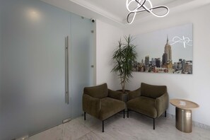 A modern interior with a cityscape painting, two armchairs, a potted plant, and a round table. - 2BR w/ Rooftop & Free Parking in Roma-Juarez (Ciudad de México)