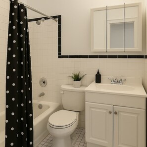 A bathroom with a toilet, sink, and mirror. - 2BR Steps from Wrigley Field (Chicago)