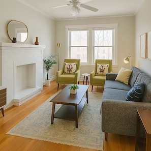 A living room with a fireplace, two armchairs, a sofa, a coffee table, and a ceiling fan. - Feel at Home in our 2BR Apt (Chicago)