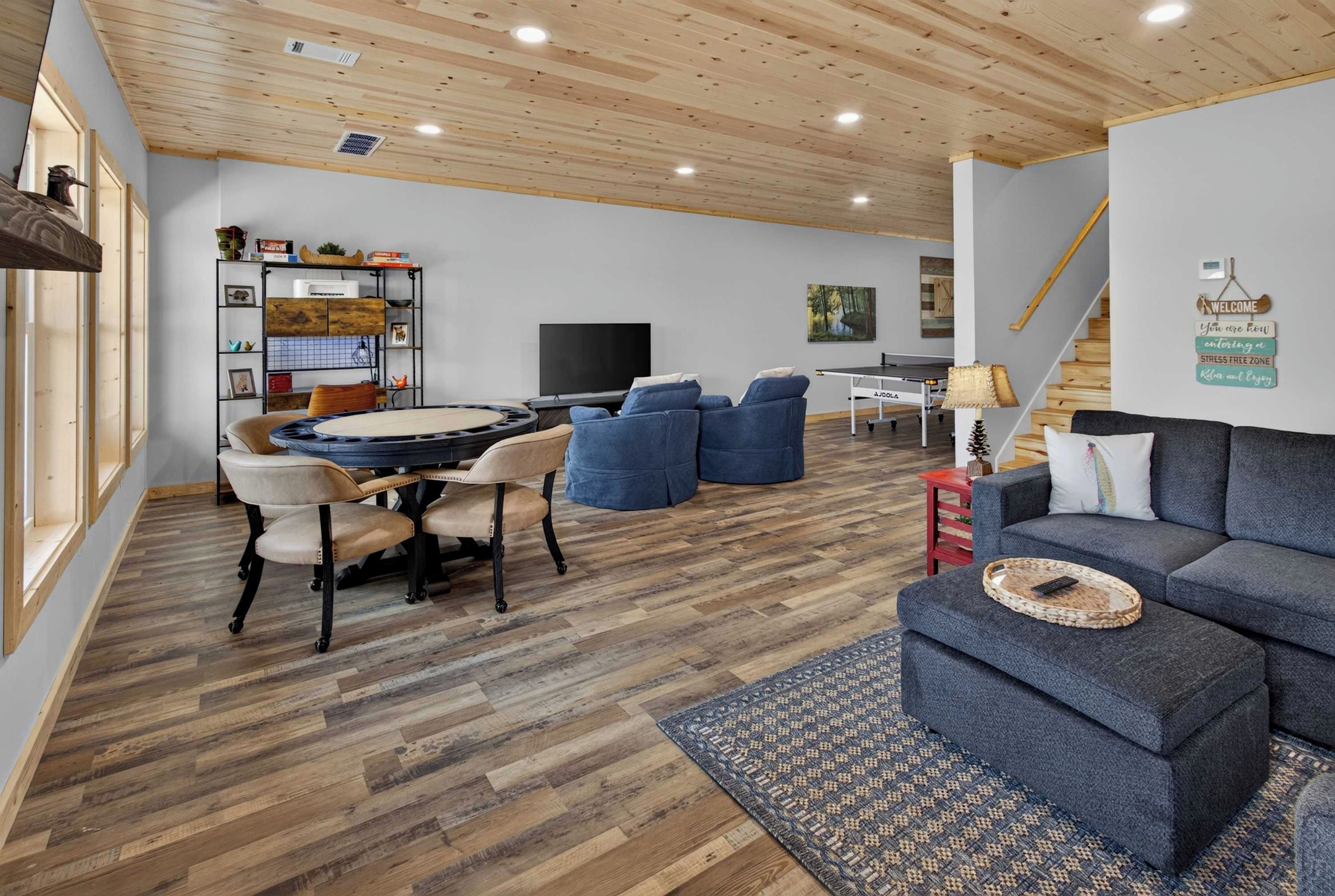 A modern living room with a wooden ceiling, a dining area with a round table, and a sofa with a woven tray.