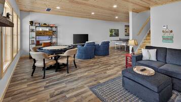 A modern living room with a wooden ceiling, a dining area with a round table, and a sofa with a woven tray.
