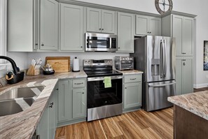 Una cucina moderna con mobili grigi, elettrodomestici in acciaio inossidabile, un piano di lavoro in marmo e un pavimento in legno.