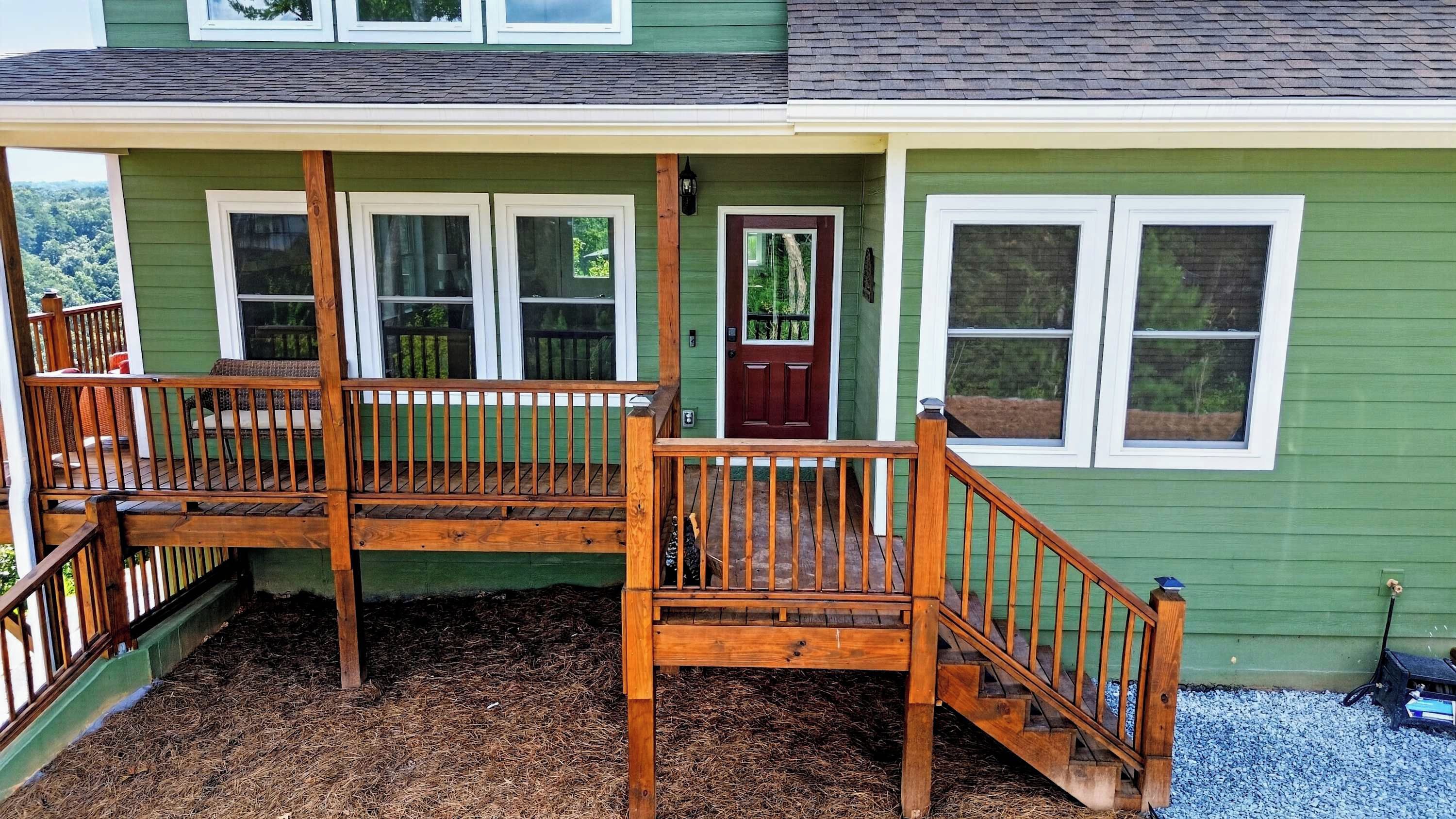 A two-story house with a front porch, a wooden staircase, and a red door.