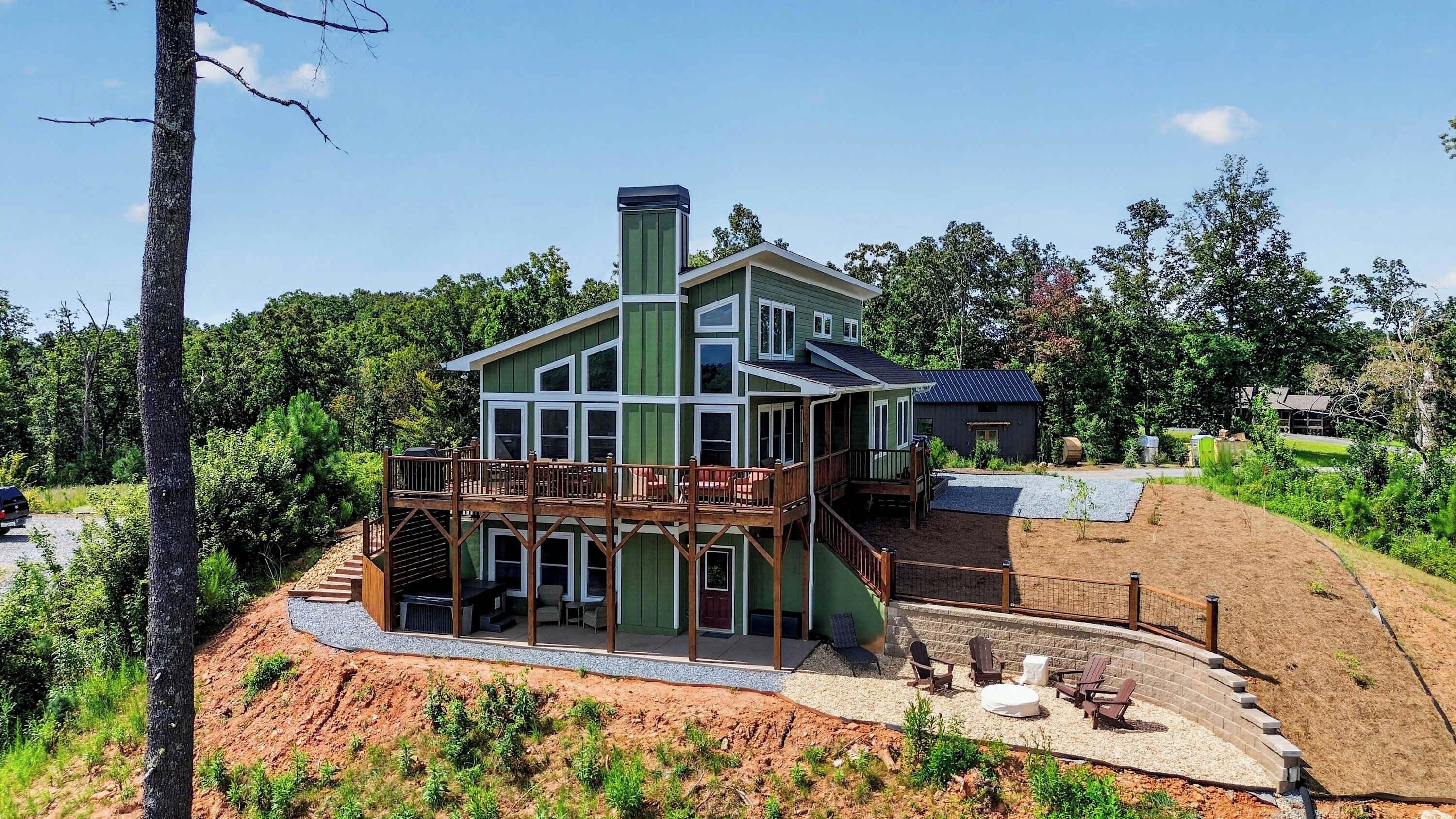 A two-story house with a deck, a chimney, and a small adjacent shed.
