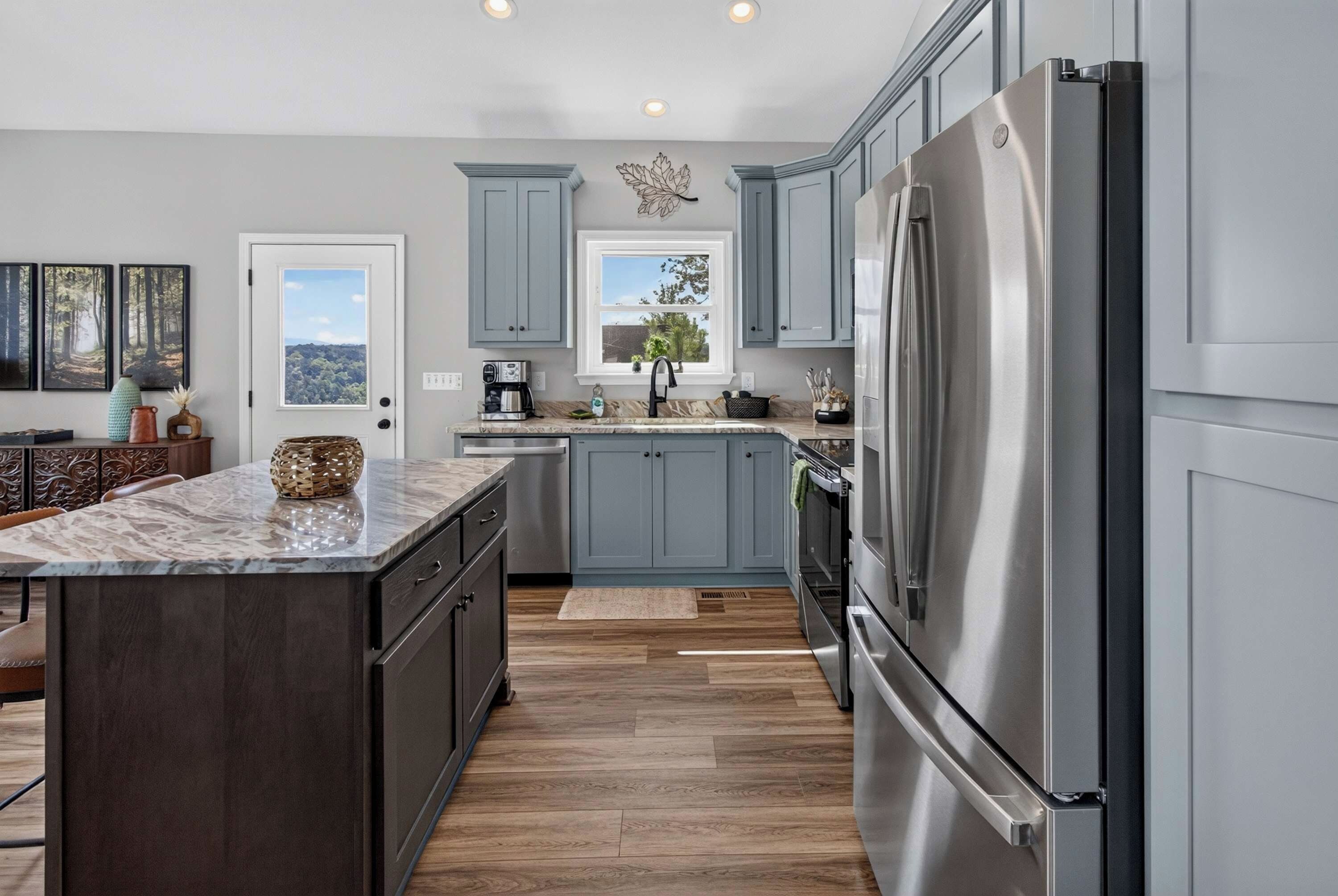 A modern kitchen with a large island, stainless steel appliances, and light blue cabinetry.