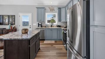 A modern kitchen with a large island, stainless steel appliances, and light blue cabinetry.