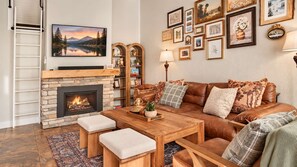 Ein gemütliches Wohnzimmer mit Kamin, einer Couch, einem Couchtisch und einem Bücherregal.