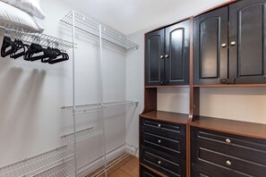 Ein begehbarer Kleiderschrank mit einem Metallregal, einem Holzkabinett und einer Kleiderstange.