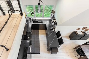Eine moderne Küche mit einem großen Fenster, einem eingebauten Herd und einem Essbereich mit Tisch und Stühlen.