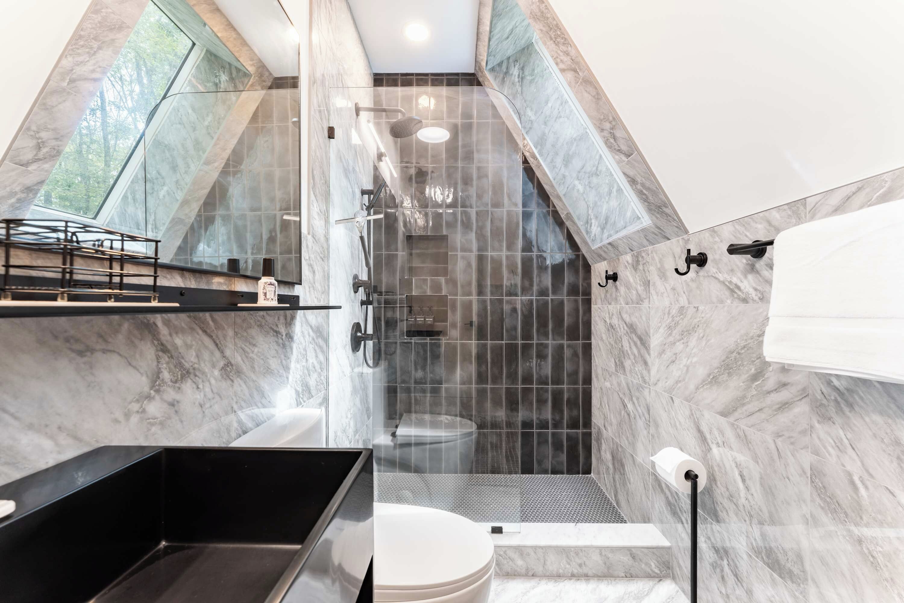 A modern bathroom with a shower, toilet, and sink.