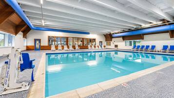 Une piscine intérieure avec des chaises bleues et un poste de surveillance pour les sauveteurs.