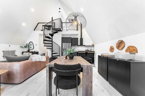 Ein moderner Lofts-Wohnraum mit Essbereich, Küche und einer Wendeltreppe.