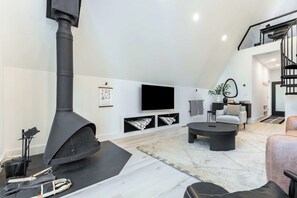 A modern living room with a large black fireplace, a flat-screen TV, and a comfortable seating area.