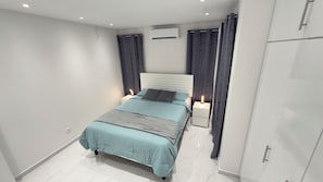 Un dormitorio moderno con una cama, lámparas de noche, un equipo de aire acondicionado y un armario.