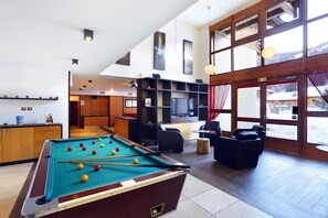 A pool table in a room with a television, seating, and large windows. - À 300 m des pistes | Piscine couverte sur place (Chantemerle)