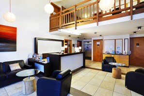 A hotel lobby with a reception desk, seating area, and a staircase. - À 300 m des pistes | Piscine couverte sur place (Chantemerle)