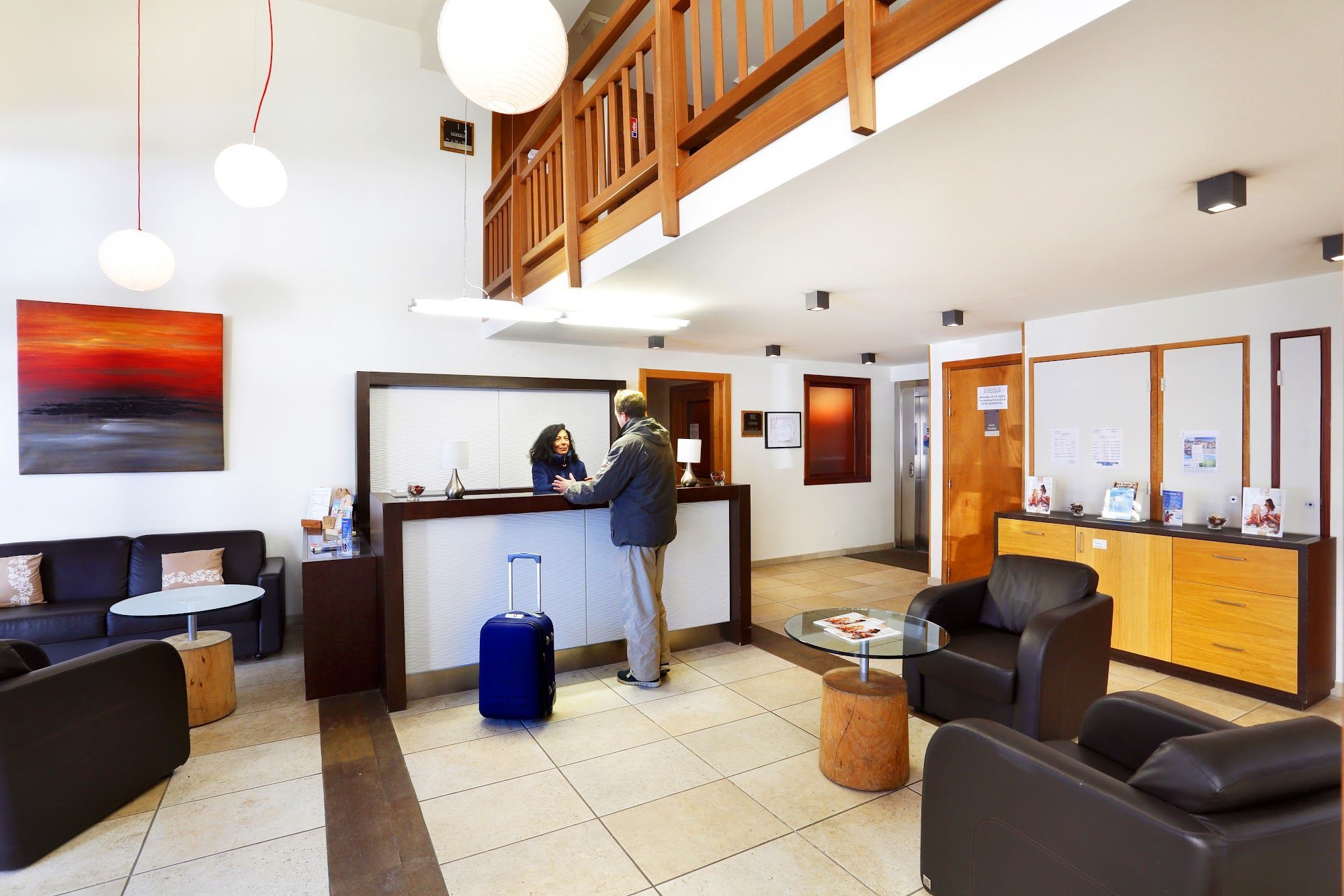 A hotel lobby with a reception desk, seating area, and a staircase.