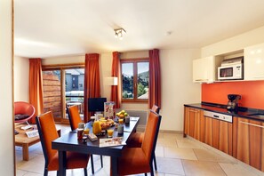 A dining area with a table set for breakfast, a television, and a view of the outdoors. - Près des pistes | Piscine chauffée sur place (Chantemerle)