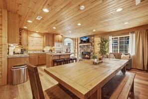 A wooden interior with a large dining table, kitchen area, and a fireplace. - Big Pine House! Hot Tub + Dog Friendly + Fire Pit (South Lake Tahoe)