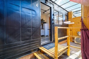 A compact, modern cabin with a wooden exterior, a small kitchen area, and a wooden bench outside. - Chalet 200m fr/ Campeche Beach w/ Garage Scj0004 (Florianópolis)