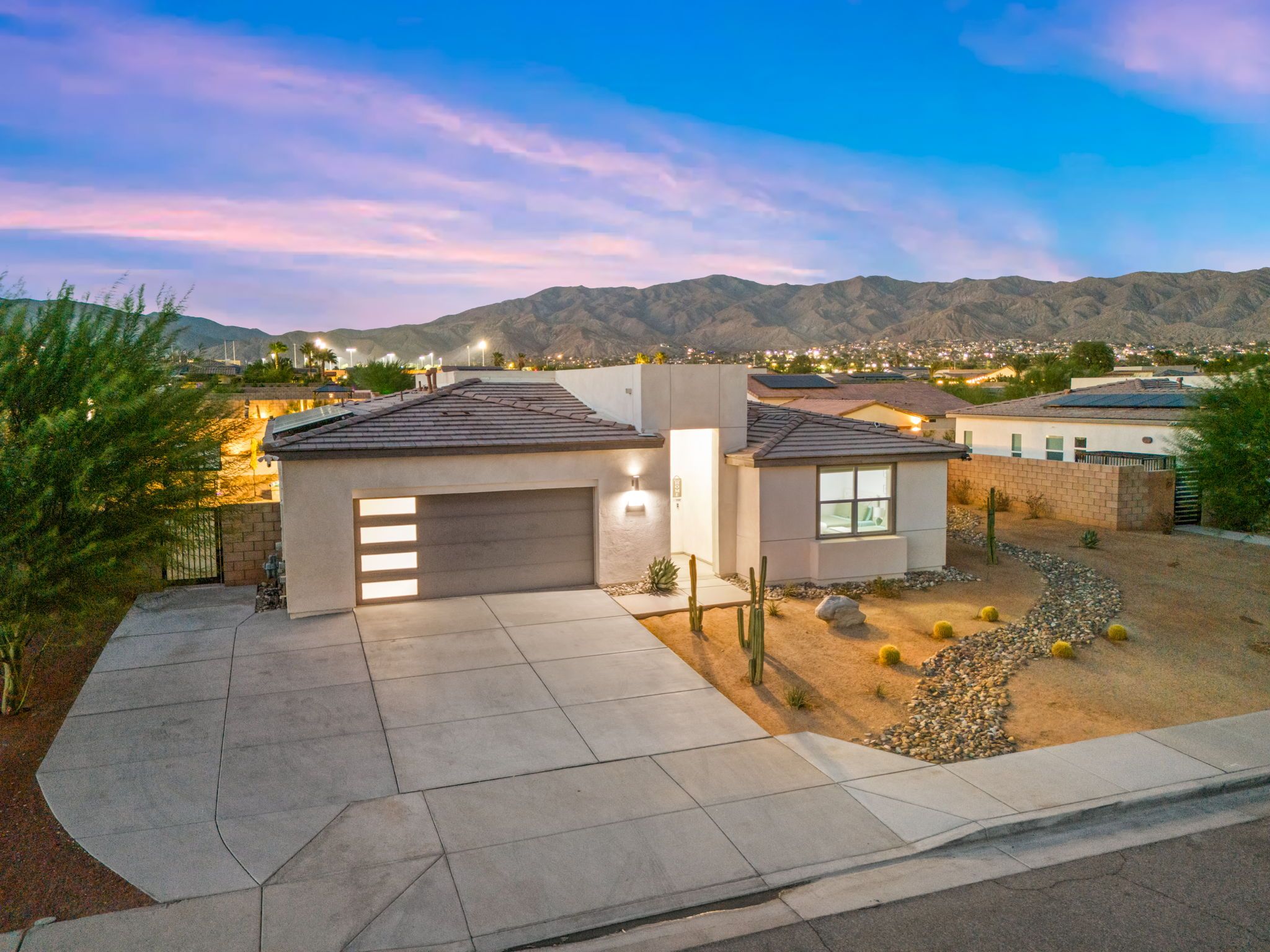 A residential property with a garage, a small patio, and a view of a town and mountains in the background.