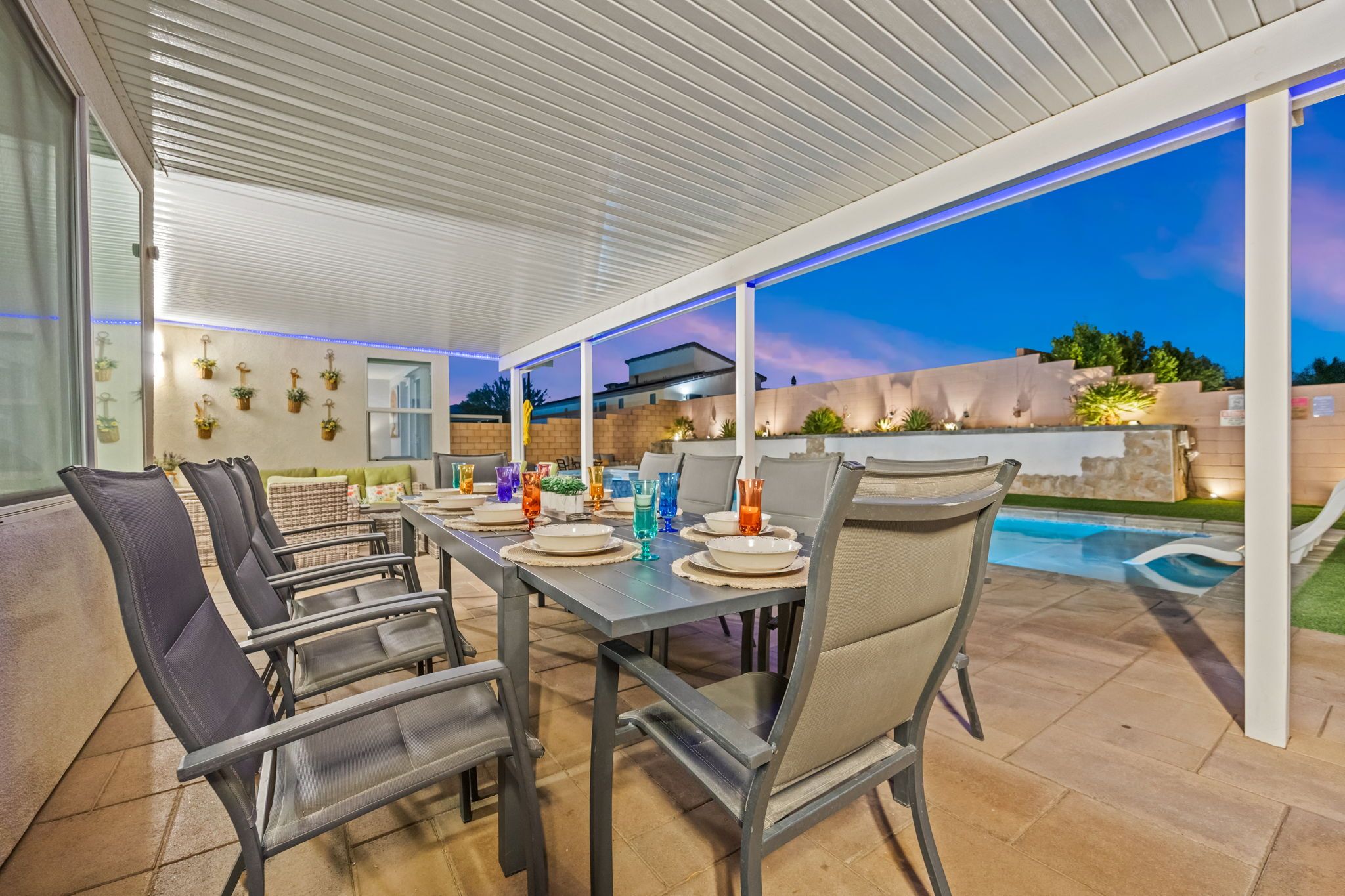 Un patio exterior con piscina, mobiliario cubierto y una mesa lista para comer.