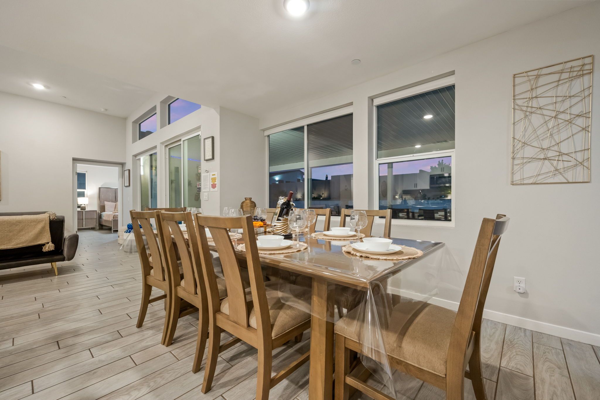 A dining area with a large table set for six, surrounded by wooden chairs.