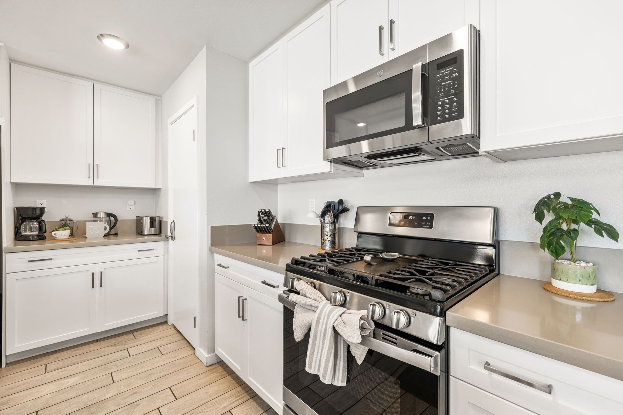 A modern kitchen with white cabinets, stainless steel appliances, a gas stove, and a microwave.