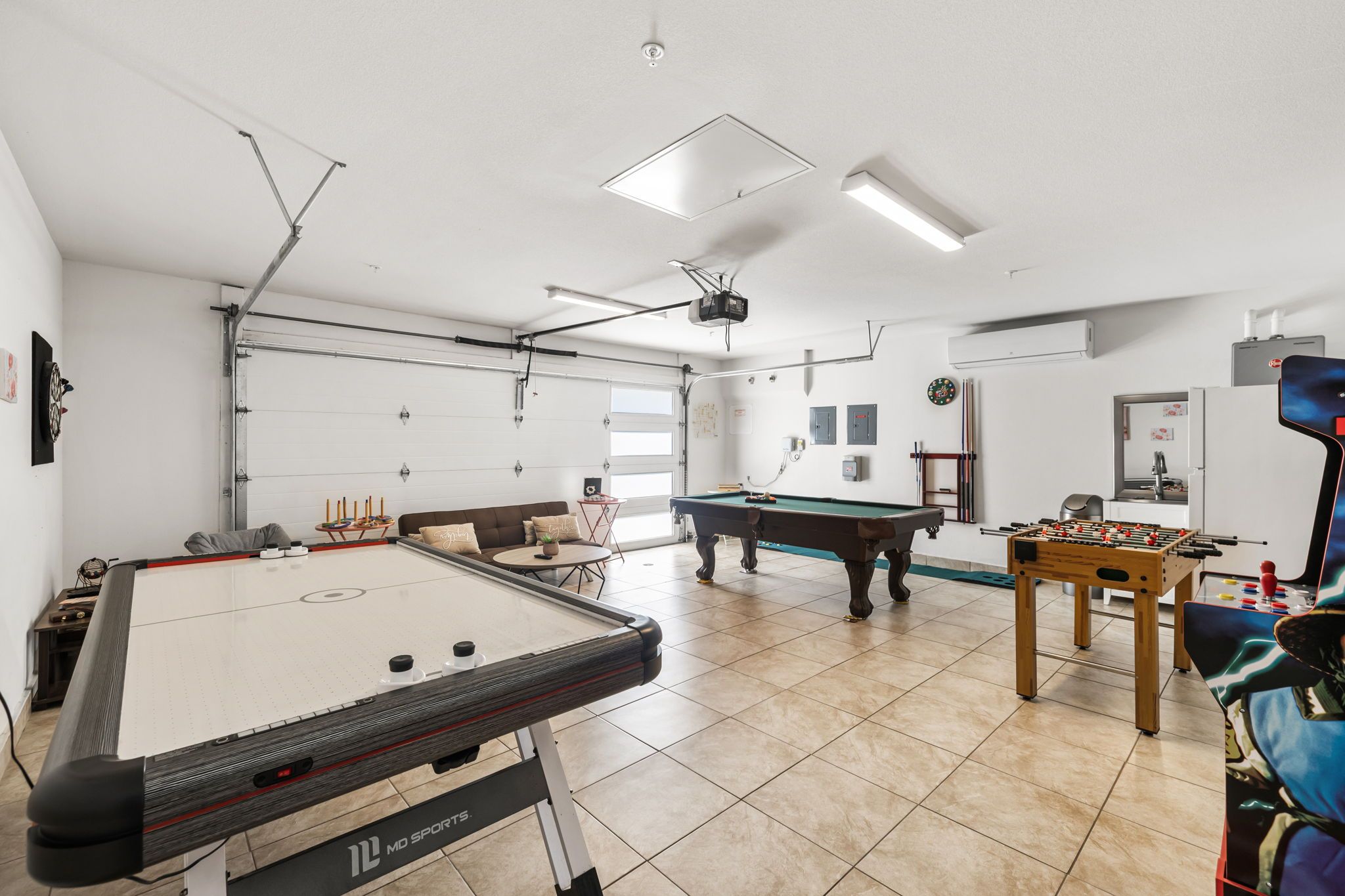 A recreational room with a pool table, foosball table, dartboard, and a billiards table.