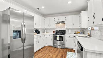 A modern kitchen with white cabinetry, stainless steel appliances, and a herringbone-patterned backsplash.
