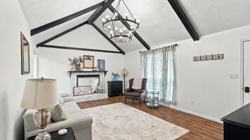 A living room with a fireplace, a chandelier, a sofa, a chair, and a coffee table.