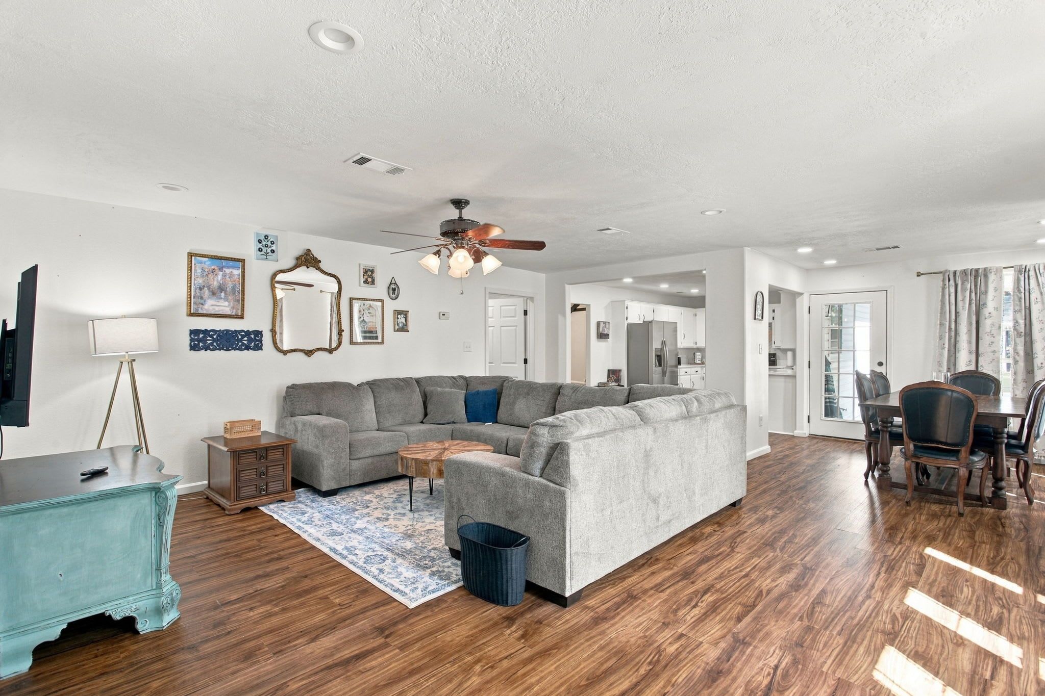 A modern living room with a sectional sofa, a coffee table, and a dining area with chairs.