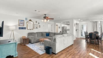A modern living room with a sectional sofa, a coffee table, and a dining area with chairs.