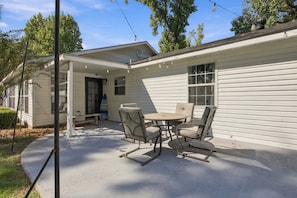A covered patio with a table and chairs, a surfboard, and a house with windows and a door. - Spacious 4BR Home in DeRidder (DeRidder)